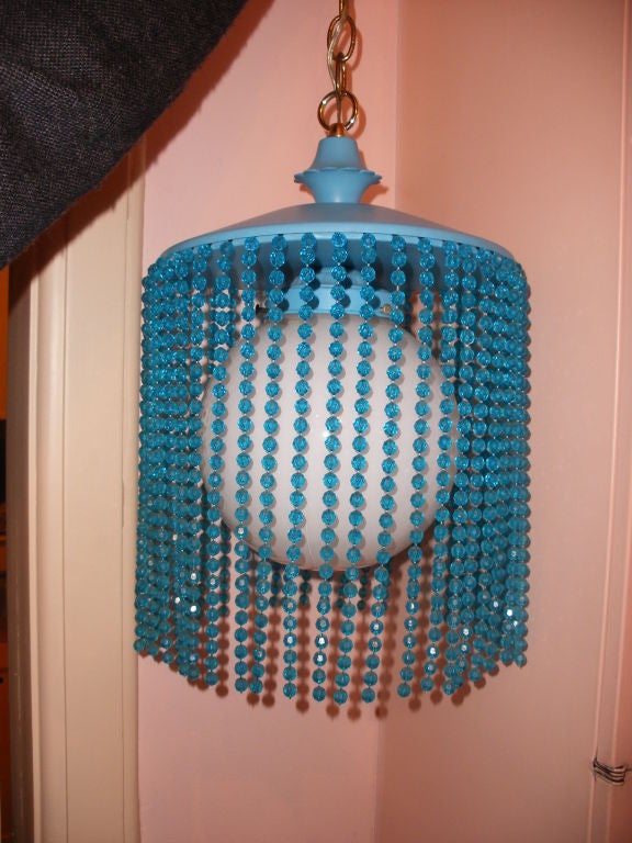 BRIGHT BLUE MOD STYLE 1960S BEADED LIGHT.  METAL TOP WITH WHITE GLASS GLOBE AND LONG STRANDS OF FUN BEADS.  DIMENSIONS BELOW DO NOT INCLUDE THE BRASS CHAIN WHICH IS 3 FT. LONG