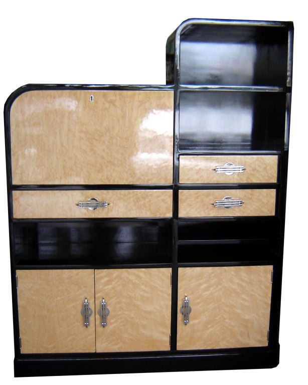 This spectacular American art deco secretary dates from the 1930’s.  High gloss black lacquer contrasts with blond birdseye maple veneers accented with bright nickel hardware.  The taller right hand section has two large display sections above two