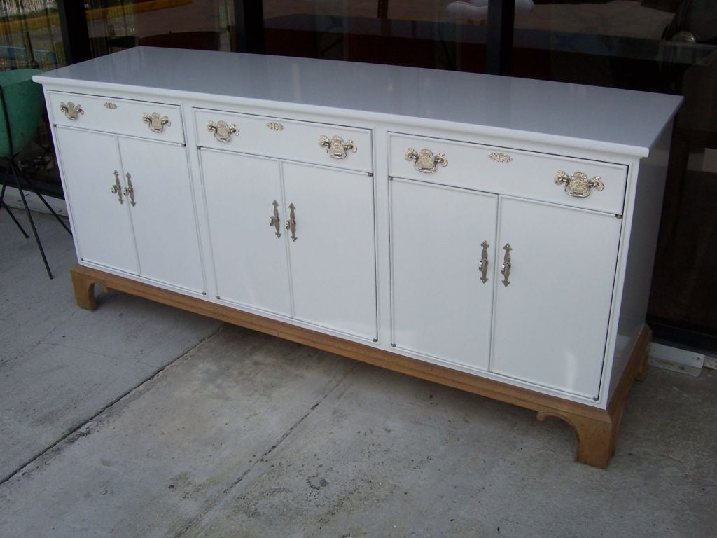 Two-toned sideboard/credenza with high gloss white and natural wood base w/ craved details.  Fixtures are nickel plated and just glimmer on this piece.  Six doors open to shelves and three large drawers.