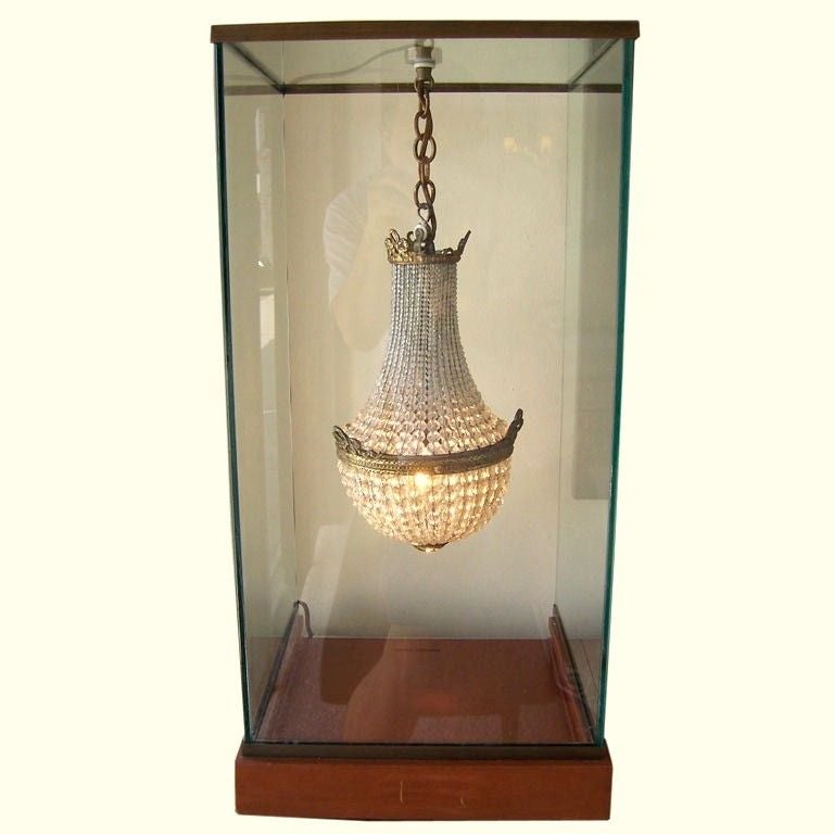 Unique bronze and crystal beaded miniature chandelier hanging and illuminated like a jewel in a glass display box.