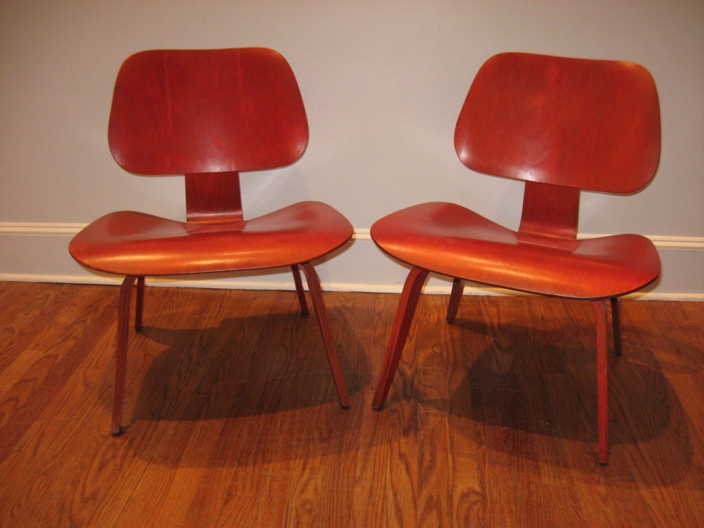 Pair of  rare early red aniline dyed LCW lounge chairs designed by Charles and Ray Eames for Herman Miller.  These chairs  are  fine early examples.  Color has become extraordinary  through time - museum quality. Rare opportunity.