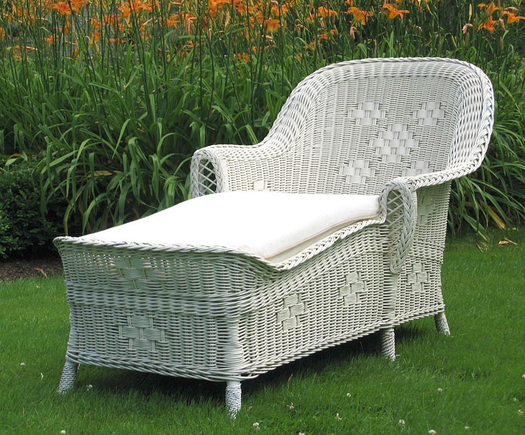 High style Art Deco American antique wicker racamier chaise lounge in white painted finish. The arms are two different levels and lengths.  Cluster of 5-diamonds woven into back panel and single diamond pattern on side and front skirts. Woven