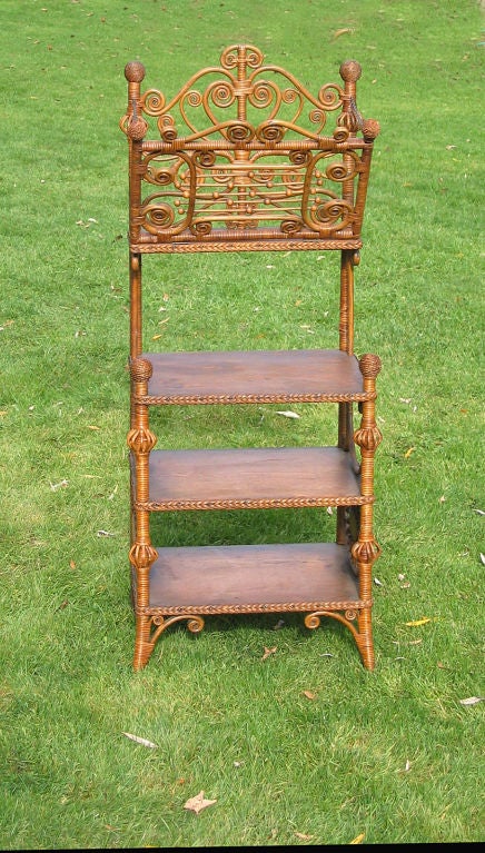 Victorian wicker music stand in natural stained finish. Highly decorated portfolio having lyre motif, atop 3 wooden shelves. Birdcage design to legs. Scrollwork with beads and curlicues throughout.