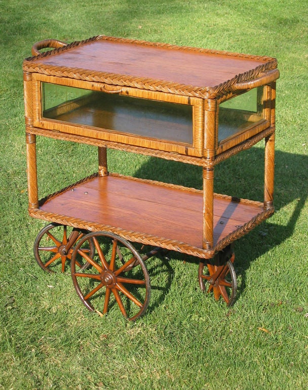 Very unusual wicker tea cart having 4-sided glass enclosed pie safe component with 2 drop down doors.  Sold oak surfaces and woven reed & cane in original natural stained finish.  Cane-wrapped handles on both ends and on both doors.  Four corner