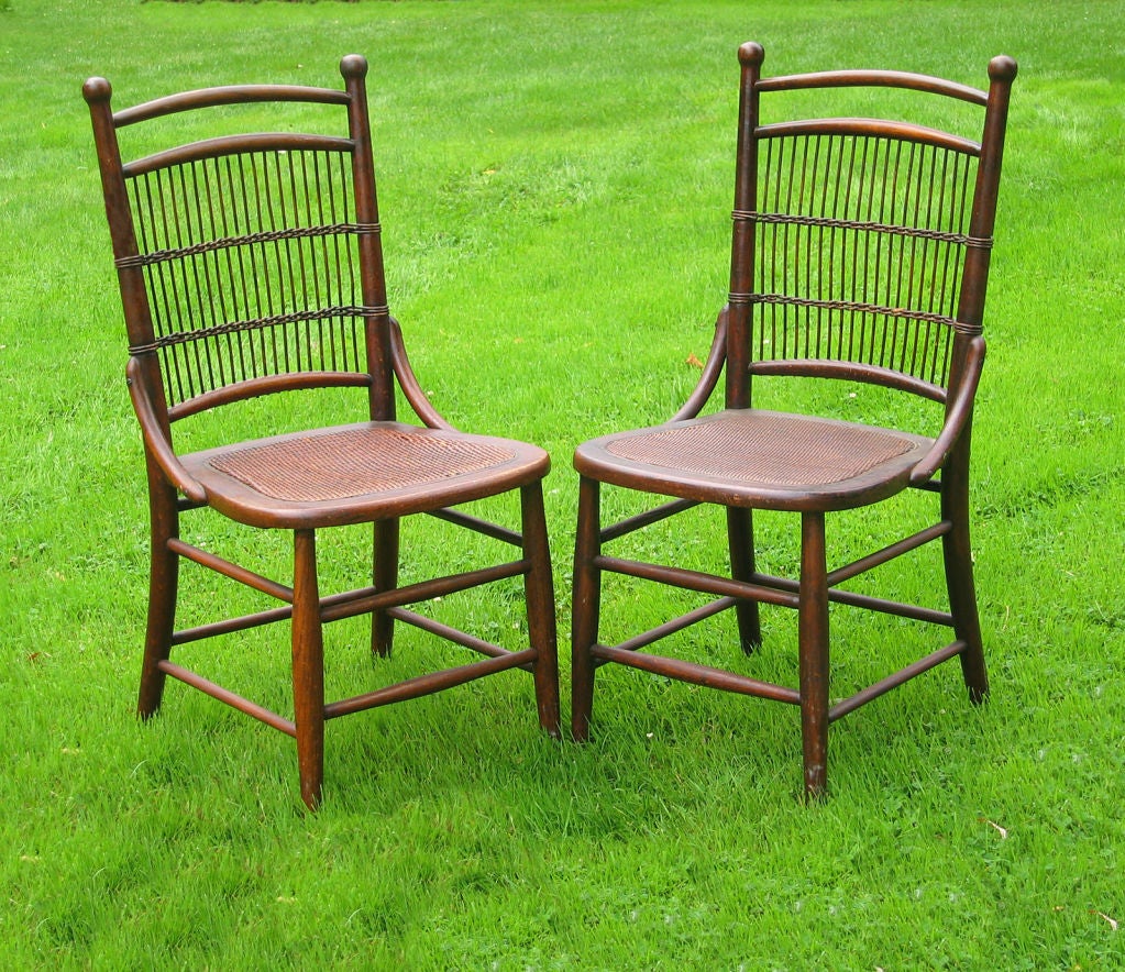 Matching pair of wicker dining chairs in natural stained finish. Oak frame, back panel with evenly spaced vertical reeds, pressed cane seats.  Additional wicker and rattan may be viewed on our website www.AmericanAntiqueWicker.com