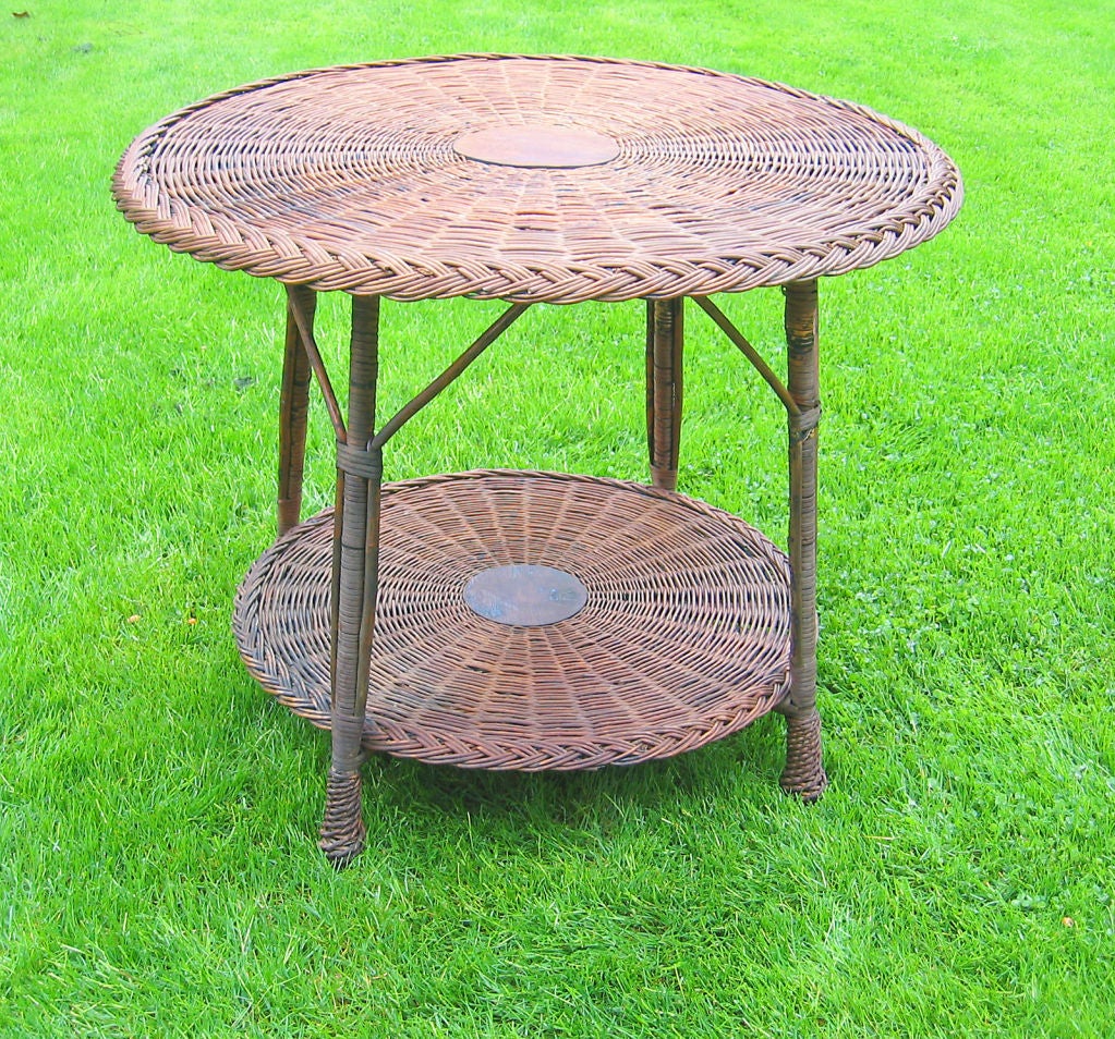 Large two tier round Bar Harbor wicker table in natural stained finish. Traditional woven top and bottom shelf with braided border and four hallmark pineapple-twist feet.