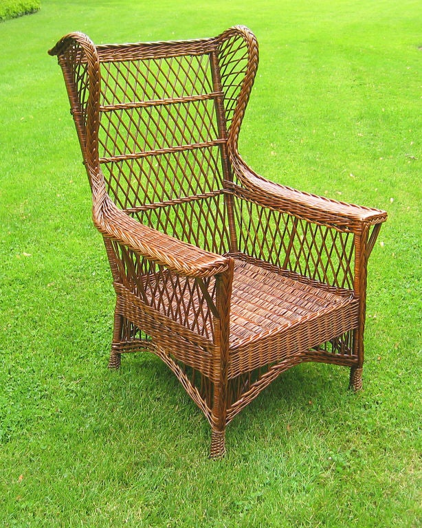 Large scale Bar Harbor wicker wingback armchair in natural stained finish. Comfortably deep-seated with a high crest, wide flat arms and level back. Four decorative twist-wrapped feet, woven seat.