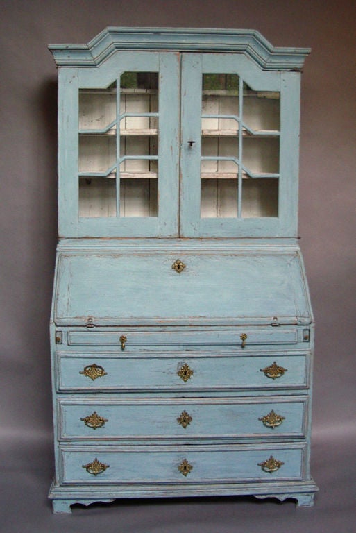 Swedish secretary, circa 1820, in blue paint. Bonnet top over a pair of glass doors in the upper section. Slant front over three drawers in the lower section. The interior has two banks of stepped drawers, two 