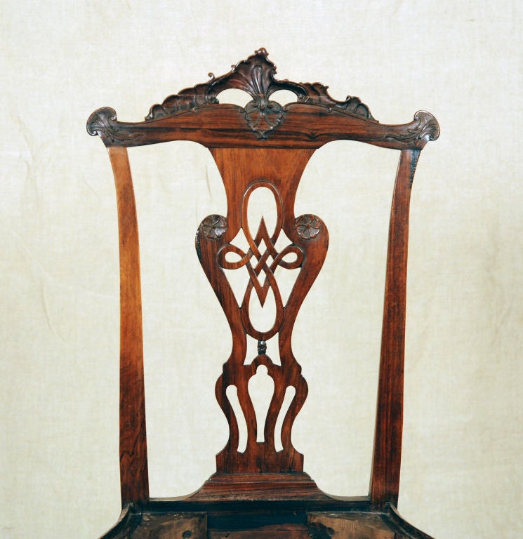 Each back with a stylized foliate crest rail above an elaborately carved splat, on a serpentine seat on cabriole legs terminating in carved pad feet, joined by shaped stretchers
