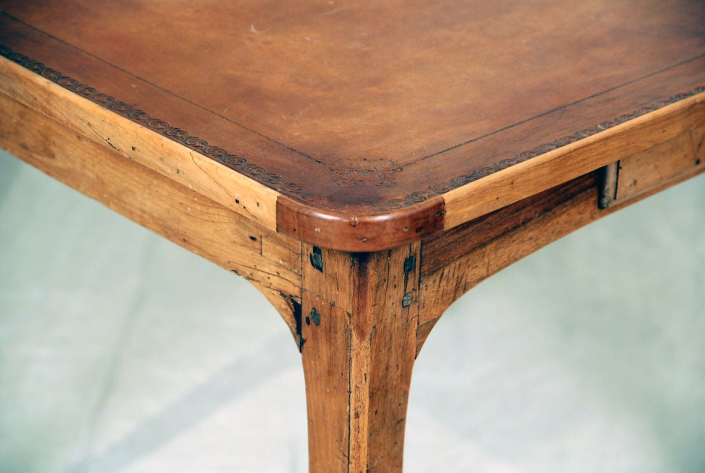 The square top with rounded corners, and a tooled leather surface above two drawers raised on cabriole legs.