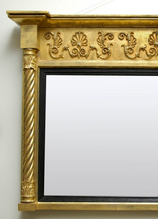 William IV giltwood overmantel mirror with breakfront cornice set above a freize decorated with swags and Prince of Wales plumes, carved spiral columns with turned leaf capitals, ebonized reeded slip.
