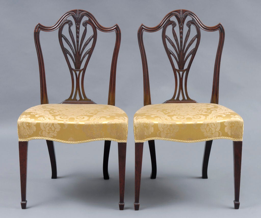 Fine pair of period Hepplewhite carved mahogany side chairs with serpentine-shaped molded top rail, the carved splat with wheat motif, straight tapering legs ending in spade feet. The serpentine-shaped seat is upholstered in a yellow silk damask.