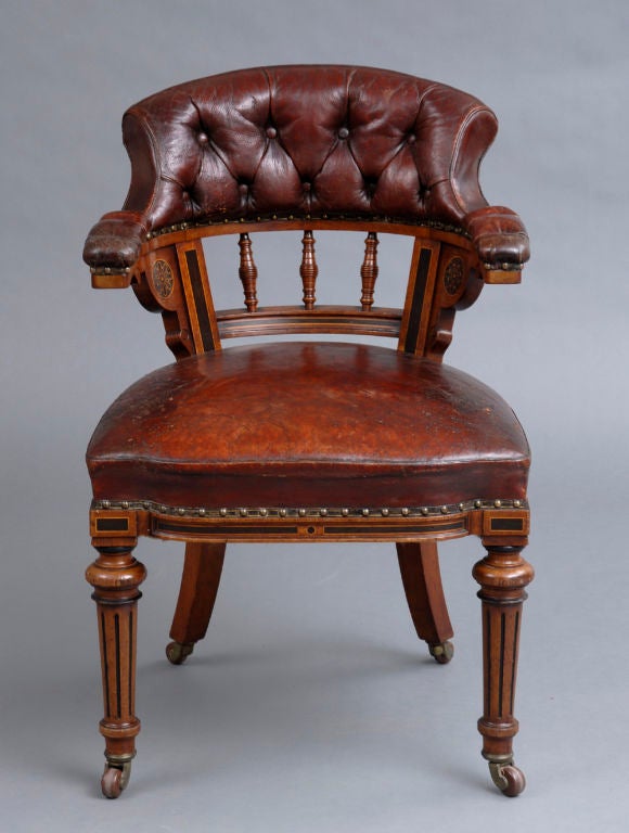 Victorian oak and ebony library/desk armchair, maroon leather shaped upholstered seat and buttoned back rest with turned spindles, the back stiles and shaped molding decorated with quarter rounds and ebonized stylized flowers, ebonized turned and