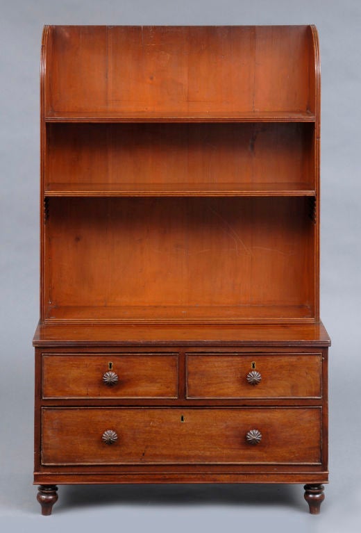 Small Georgian mahogany bookcase, the upper section having shaped reeded sides, two open adjustable shelves with reeded edges, above two over three graduated cock beaded drawers, carved melon-shapaed knobs, raised on turnip-shaped feet.