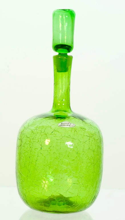 This chartreuse green decanter features a crackle-finish. It was made by Wayne Husted for the famed Blenko Glass Company. Features original label.