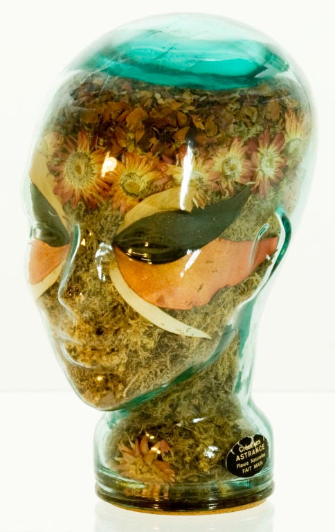 A very unusual glass head sculpture filled with dried flowers carefully arranged to resemble a Carnivale mask.