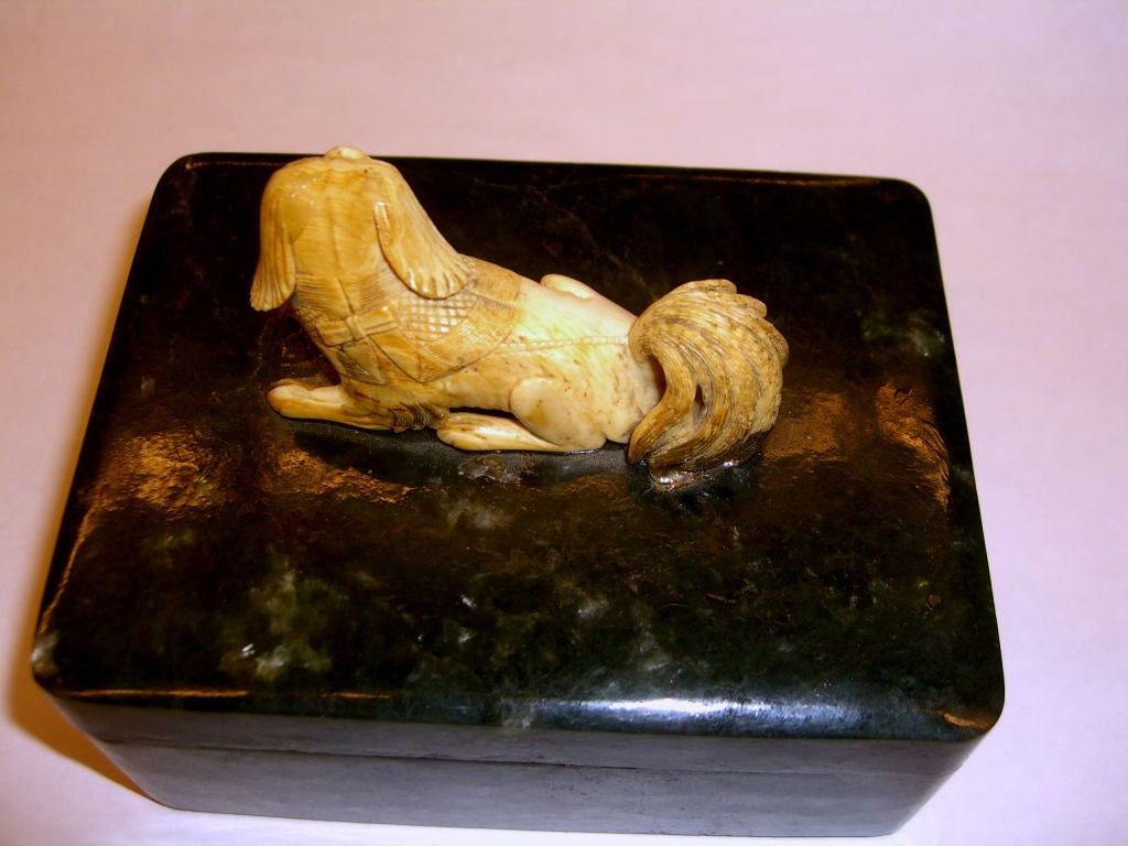 An unusual box hand carved out of Spinach jade, with a hand carved ivory Foo dog on top. This box dates to the 19th Century. The dog has been re-glued and there is some glue residue.