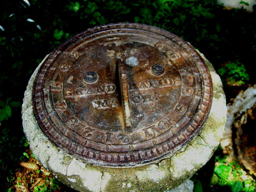 A great 1920-30's Iron Sundial marked Compliments of Grands Rapids Michigan, mounted on a stone rotating top and stone base. The stone had been painted white but quite a bit of the original paint is gone. The sun dial is set for grands rapids,