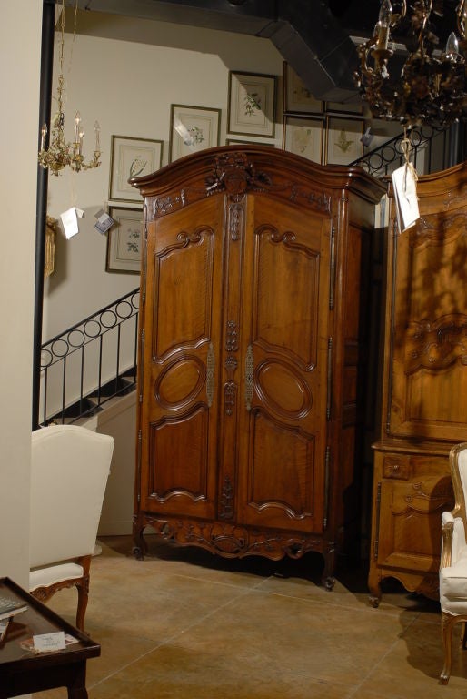 A French Louis XV period walnut Provençale armoire from the second quarter of the 18th century, with hand carved floral décor and bow motif. Born in Provence during the early years of the reign of King Louis XV 
