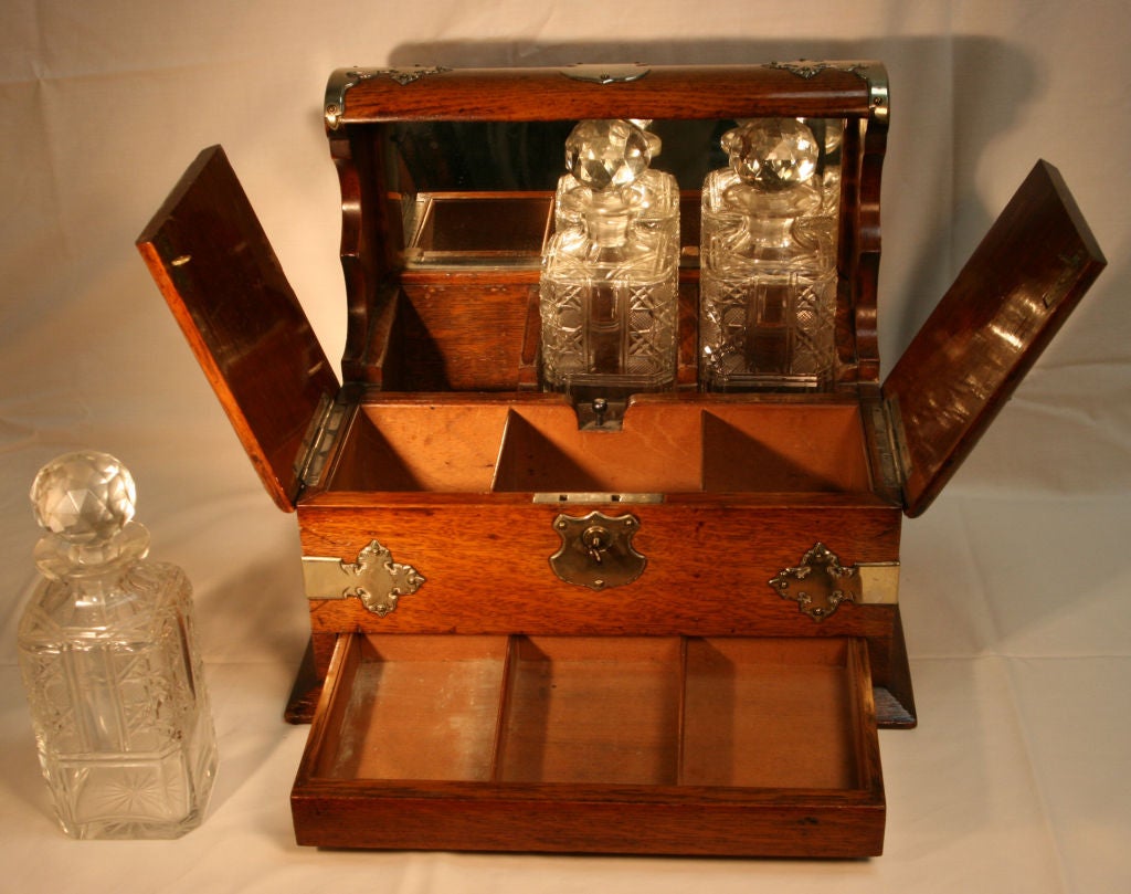 Superb English Oak and polished steel Tantalus with presentation cartouche dated 1905.  Box earlier c.1875   Tantalus so called because it 'Tantalises' the Butler in that he can see the 3 liquor decanters but cannot get to them because they are