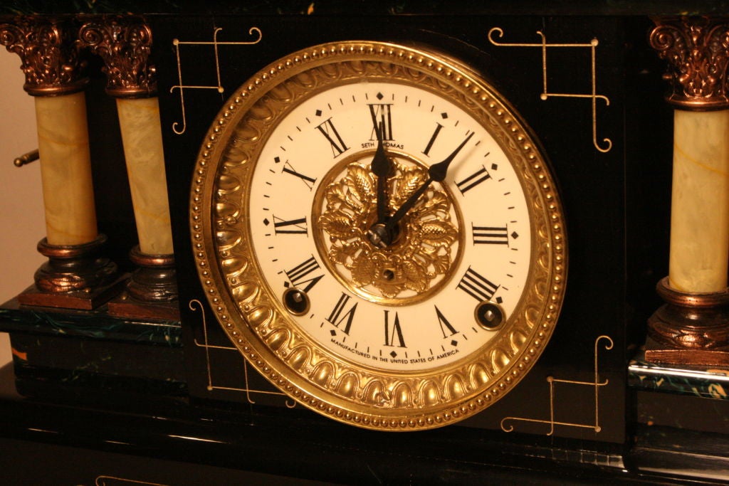 Seth Thomas Adamantine (Faux marble) Mantel Clock with corinthian columns (Faux Onyx) either side of dial.  8 day with gong strike hourly and half hourly.  Enamel dial with Roman Numerals.  Base of dial states 'Manufactured in the United States of