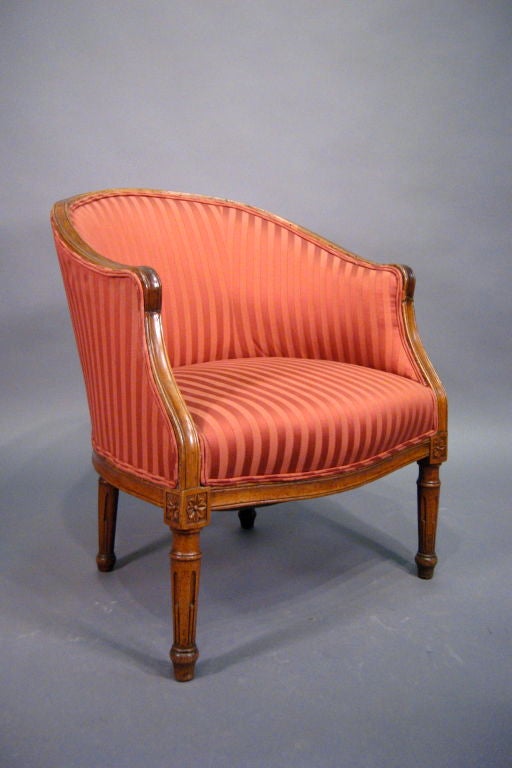 A fine Restauration period upholstered Bergere, constructed in Walnut with Louis XVI-style carved designs on the exposed rails and legs. 

The chair featuring a fluid arched back, upholstered on both sides, and with an exposed shaped edge. The