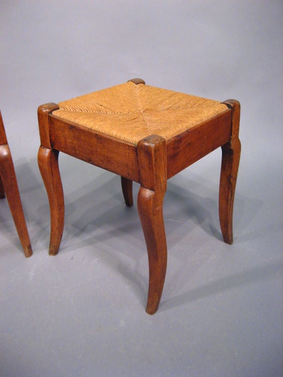 A pair of provencial Louis Philippe foot-stools, each with Walnut construction & rush woven tops. Dating from the second quarter of the 1800s, and French in origin. <br />
<br />
Each bench with exposed Walnut frame atop four tapering legs of
