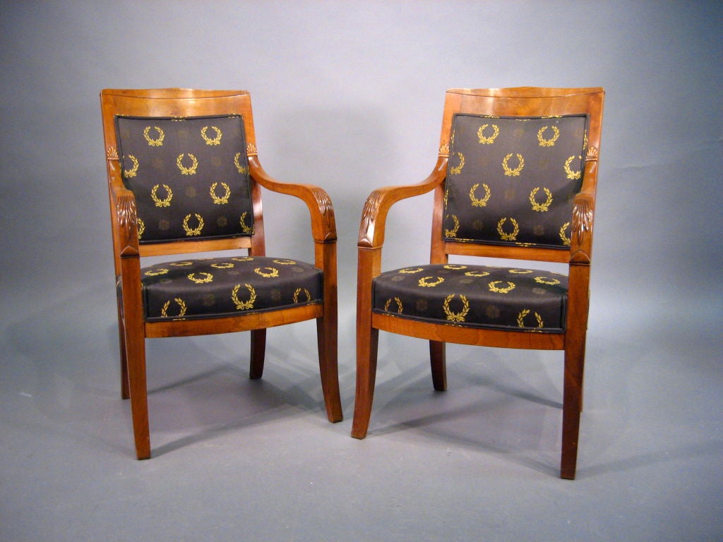 A refined pair of Empire design Fauteuils, each constructed in richly-figured mahogany. The pair French in origin, and dating from the fourth quarter of the 1800s.

Each chair with upholstered seat and back surrounded by exposed frames. The seats