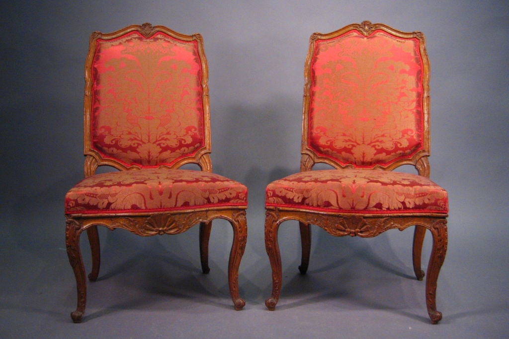 A fine pair of Regence Period Side Chairs, with exposed Beech-wood rails and aprons around upholstered seats. Dating from the first quarter of the 1700s, and French in origin. 

The shaped backs featuring serpentine forms on all sides, and crestings