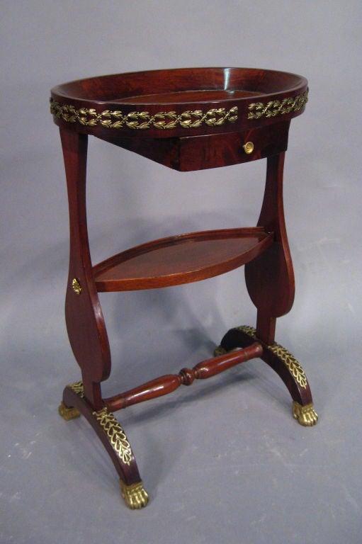 A richly-adorned 'vide-poche' table, known so for its recessed surfaces and dish-like design. With dark mahogany exterior and mounted with gilt-bronze throughout. Dating from the early 1800s, and French in origin. 

The Table with a single sliding