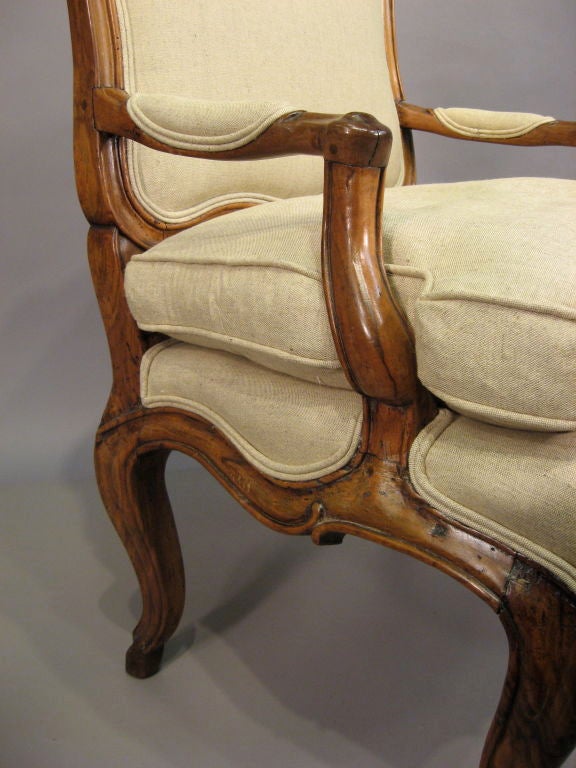 An Italian Rococo-design Fauteuil, with an exaggerated curvilinear design of French inspiration executed in Walnut, upholstered with a removable cushion. <br />
<br />
The chair with moulded edges & sparingly-applied carved accents throughout the