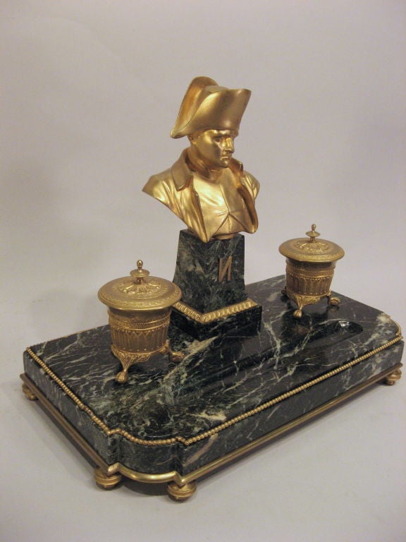 An Encrier set with richly-veined Verde Antico marble base mounted with pair gilt-bronze inkwells flanked on either side of  a Napolean bust. The marble base with pen tray rest on shaped circular feet. The Encrier set dates in the 19th Century and