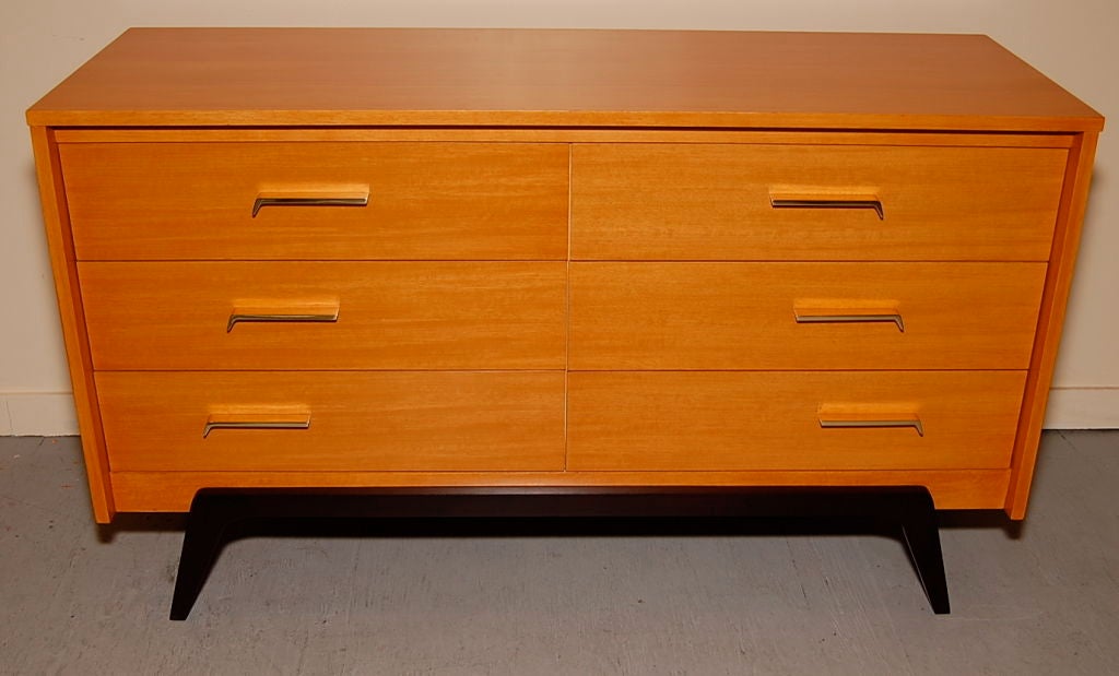 Six drawer dresser by Johnson-Carper, interesting descending angled brass pulls with a amber hued body resting on a pair of espresso lacquered arched legs.