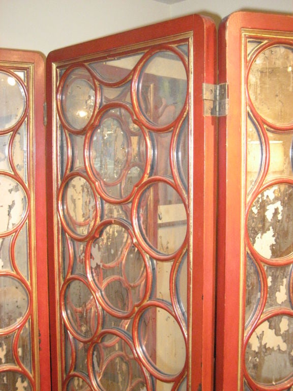 A dramatic James Mont style 3-panel screen in the Asian manner, in red lacquer with distressed mirror back panels, circa 1940.