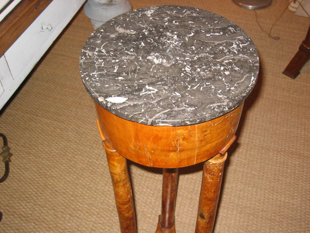 A French, Charles X period pedestal in burled elm, circa 1820, with three turned legs and a circular grey marble top.