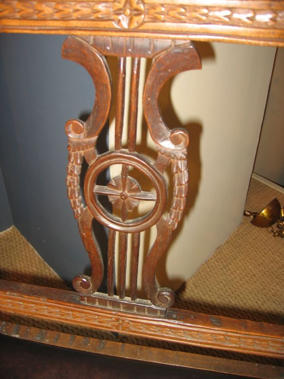 An early 19th century Northern Italian armchair in the neoclassic style with a carved lyre back panel and a leather-upholstered slip-in seat.