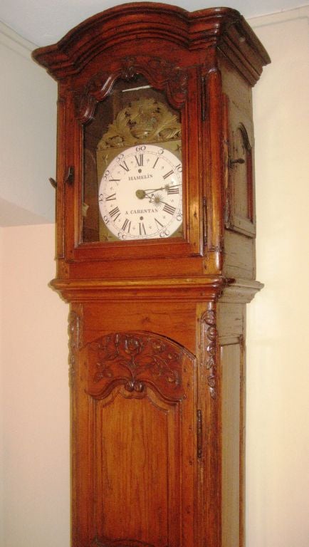 A very fine tall case clock from Normandy, France circa 1770, the case in pine with floral carvings on the doors. The mechanism is of the period with an enamel face signed 