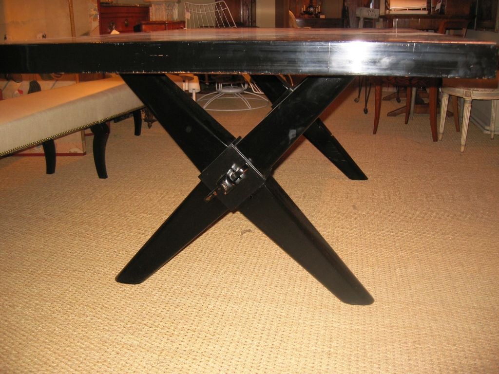 An unusual bleached and ebonized mahogany dining table, in the manner of Robsjohn-Gibbings, circa 1930-1940, with a bold "x-form" ebonized trestle base, the top with pull-out extention supports on each end (extends an additional 13"