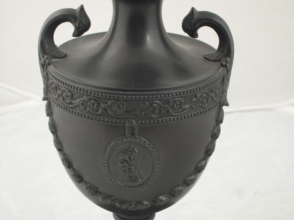 Palmer black basalt vase,  Englsh, late 18th century, classical shape with scrolled handles, medallions of Hercules and of a floret above laurel garlands and bordered with arabesque floral and foliate banding; mounted atop a later Wedgwood