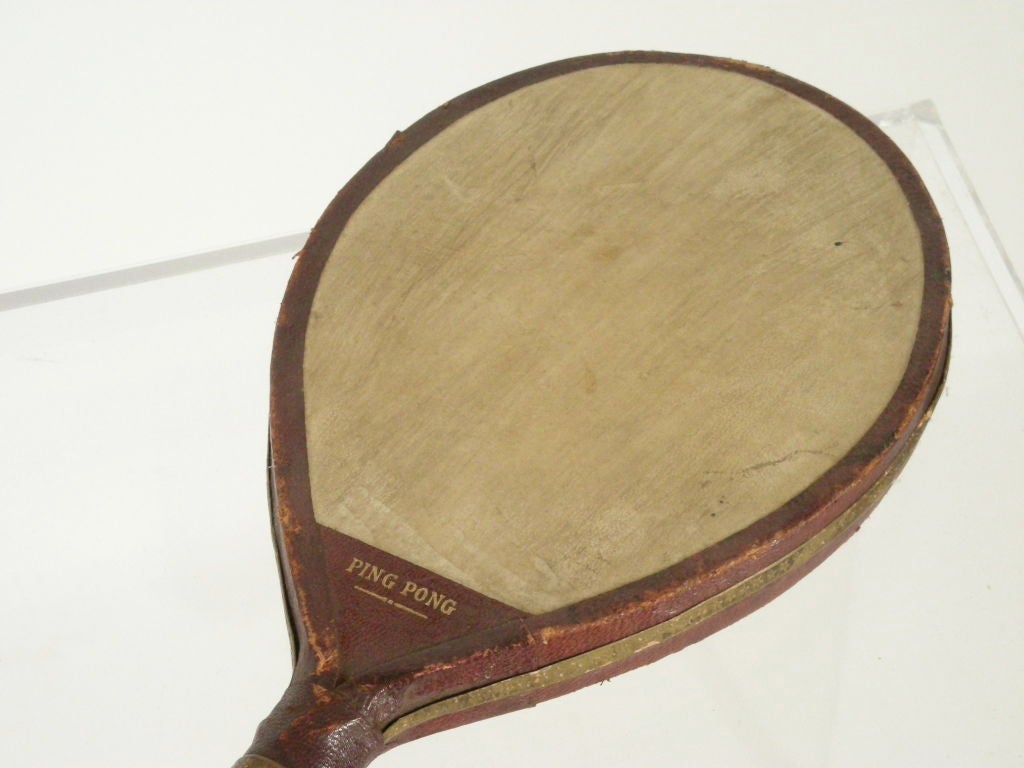 Pair of vintage English or American ping pong paddles with wooden handles and leather wrapped wood frames, embossed in gold with 'Ping Pong' on the neck of each, and vellum centers.  Great as decoration on  a wall or table.