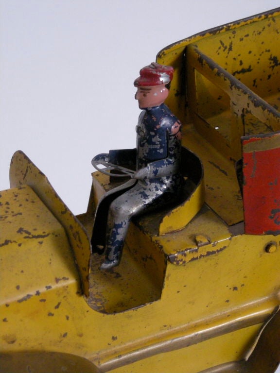 Yellow and red painted pressed steel toy friction dump truck with removable driver by made by the Dayton Toy & Specialty Co. , Dayton, OH, c. 1909-1935.