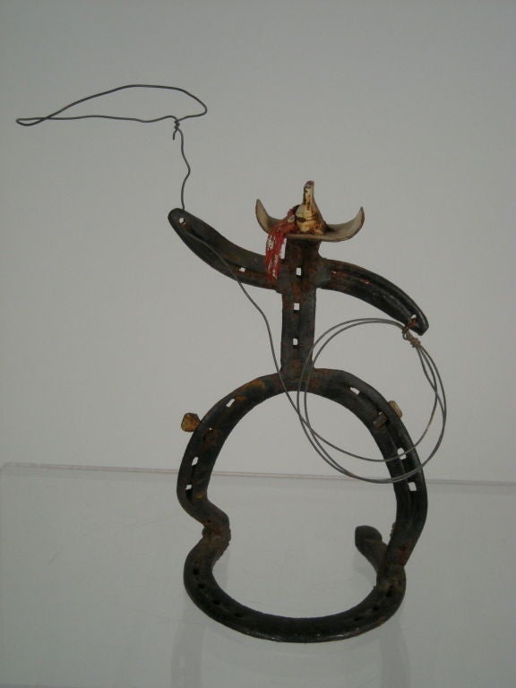 Whimsical folk art figural sculpture of a cowboy with a lasso, made from iron horse shoes, cast metal and wire, complete with spurs.