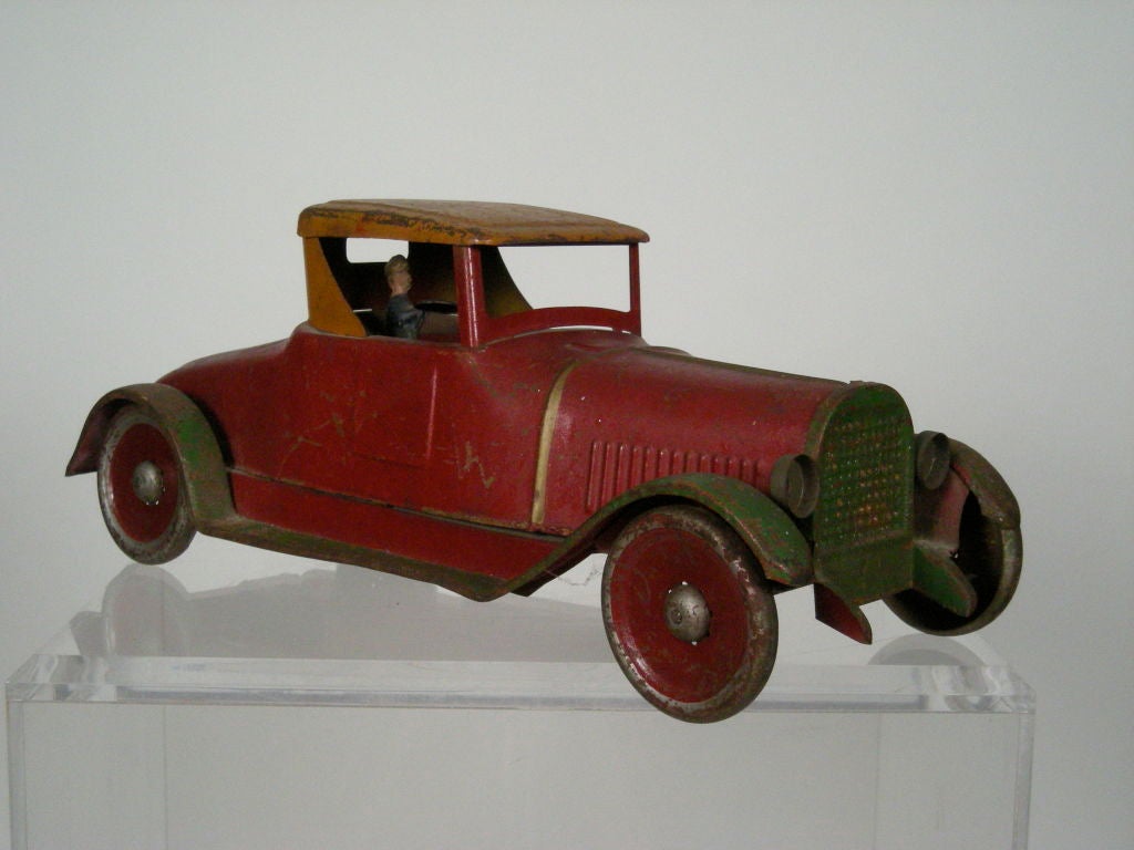 Antique Dayton Toy Company roadster coupe friction toy car in all original red, green and yellow paint, with removable painted cast iron driver who can sit on the right or left hand side. Great scale and color. Provenance: A private New England folk