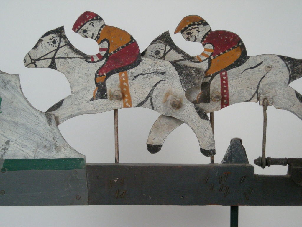 American folk art horserace whirligig with jolly, bobbing jockeys, in painted tin. When wind turns the blades, jockeys on horseback move as in a horserace.Mounted on a green painted heavy metal base. American, early 20th century.<br />
Provenance: