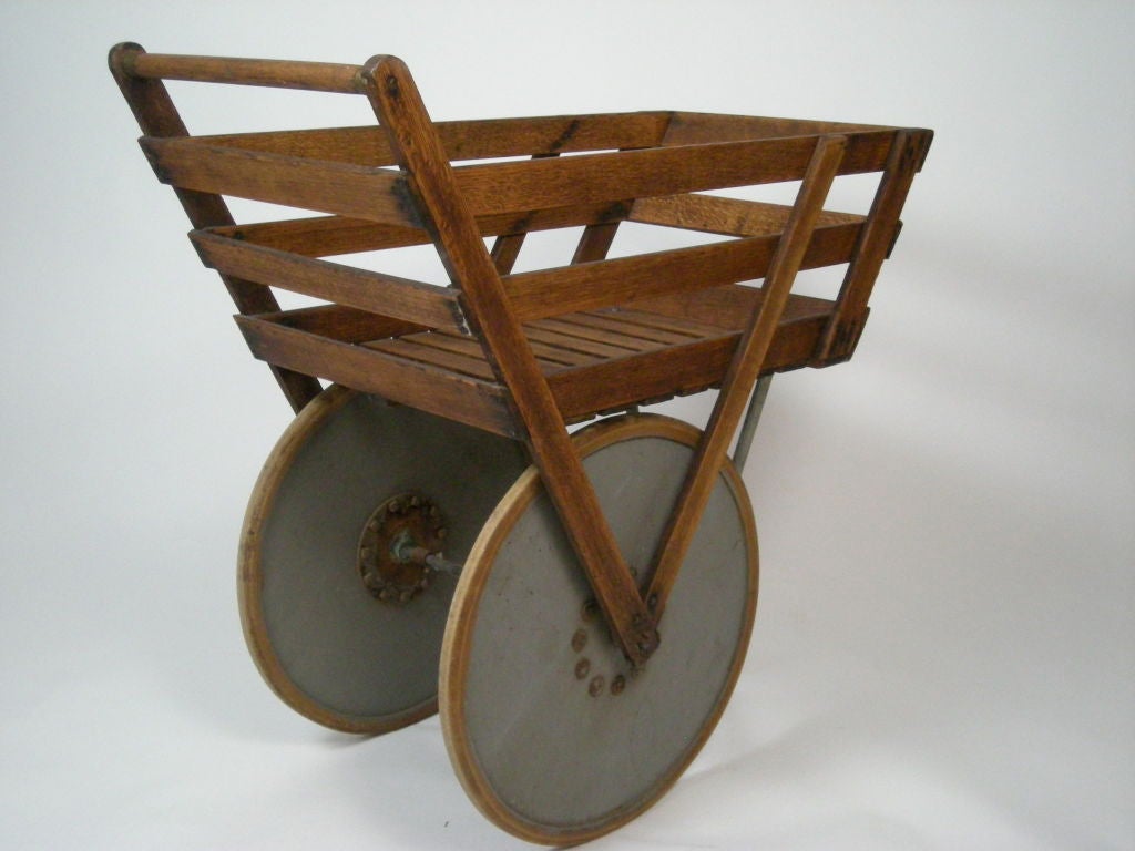 Graphic and unusual late 19th century factory cart from Ohio in oak with large painted wood wheels, metal strut,<br />
Ideal for use as a bar, plant stand, or functional sculpture.