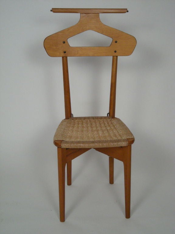 Italian valet chair in oak, maple and teak, with rush seat, the top of cut out hanger form with brass extending rods (for neck ties or other garments), and lift-top seat which opens to reveal hidden storage compartment for watch or jewelry. Signed