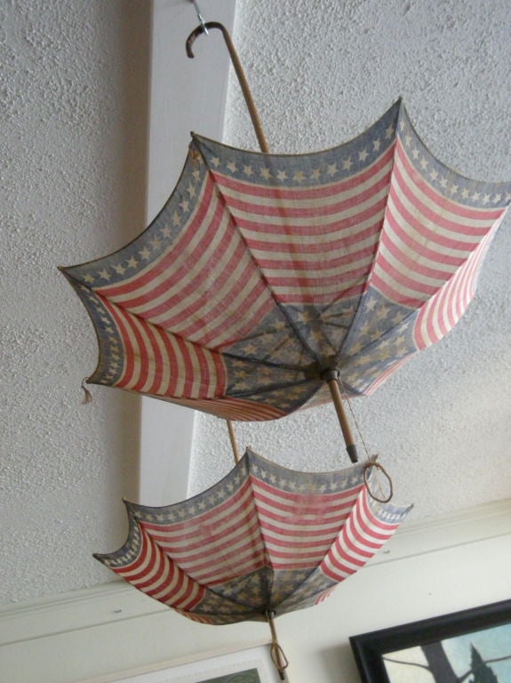 Pair of American flag-printed cotton parasols with bamboo shepherd's crook handles.<br />
Wonderful late 19th century Americana, celebrating the Centennial of July 4, 1776.<br />
Could be adapted as hanging light fixtures.