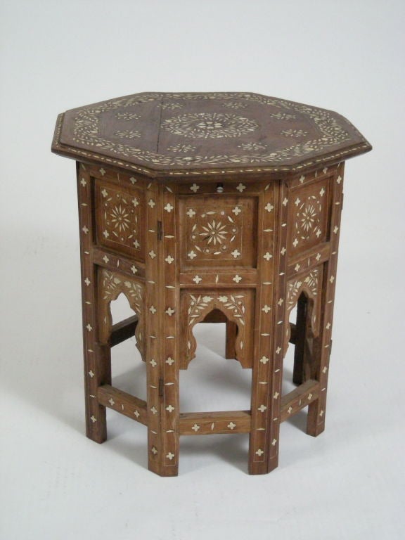 Antique Indian table in teak, the folding base with arcade cut outs and stretchers connecting the legs and octagonal top all elaborately inlaid with floral and geometric motifs in ivory.