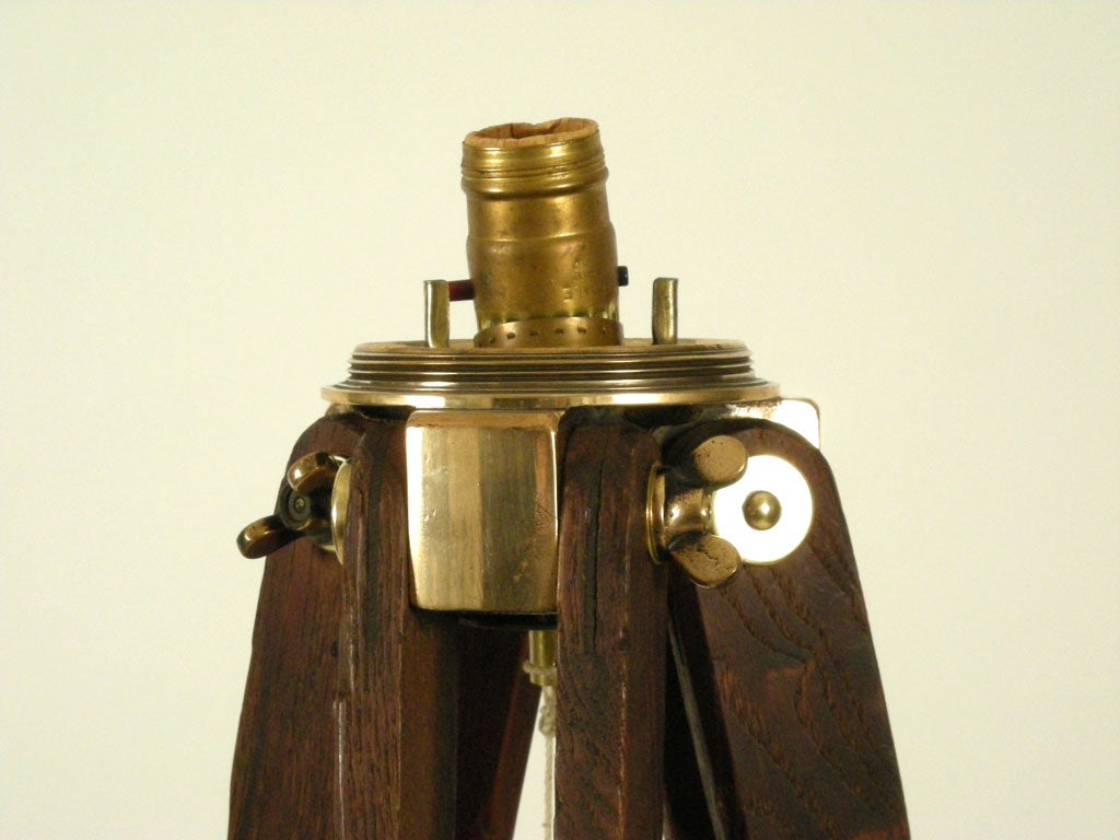Oak and brass mounted surveyors tripod with original brass hanging plum bob. High quality wood and brass fixtures, newly wired as a floor lamp. With new kraft paper empire shaped shade.