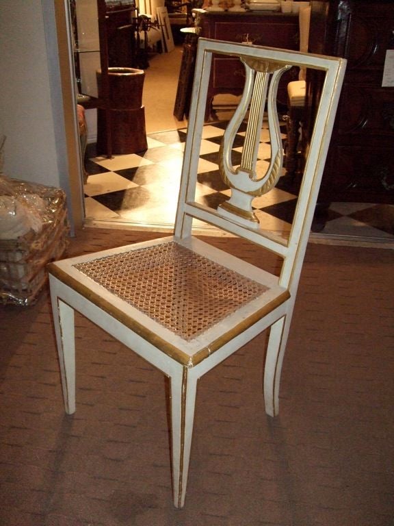 Set of six paint and gilt side chairs with lyre backs and caned seats.